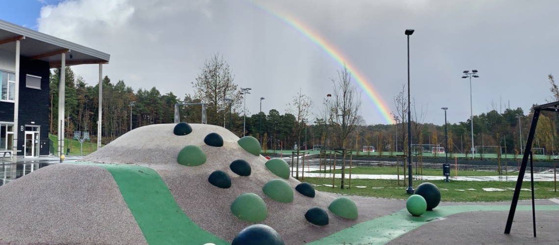 Skolegård med regnbue på himmelen