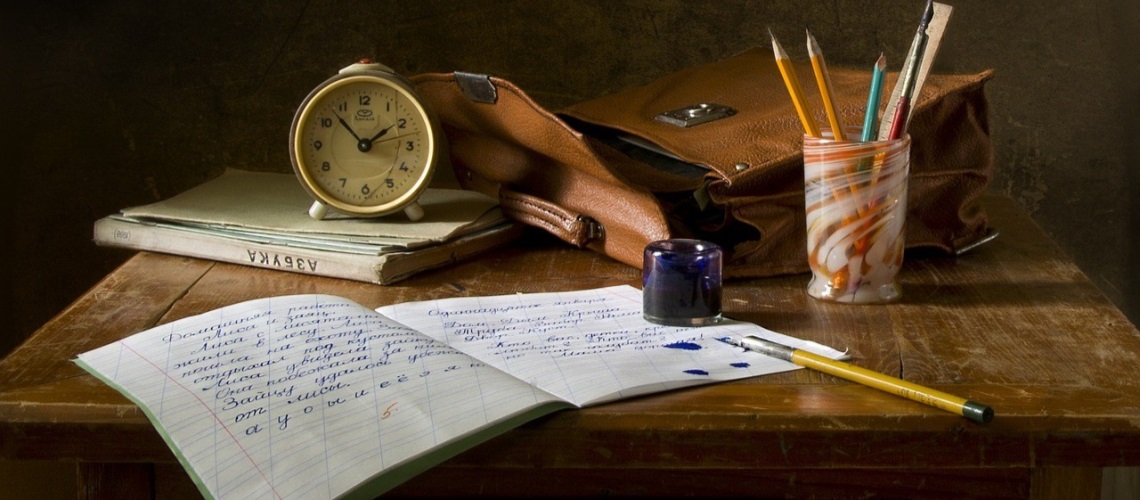 Bilde av et skrivebord med skrivesaker, en klokke og en skinn-veske.