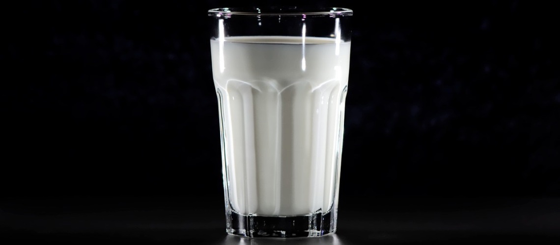 Melkeglass med melk mot svart bakgrunn.