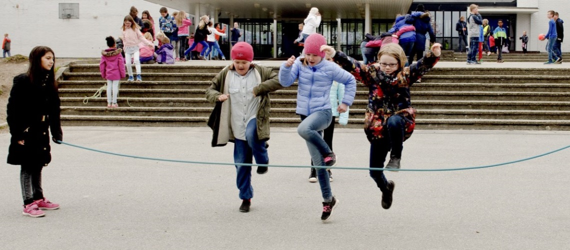 Barn som hopper tau i skolegården. Foto.